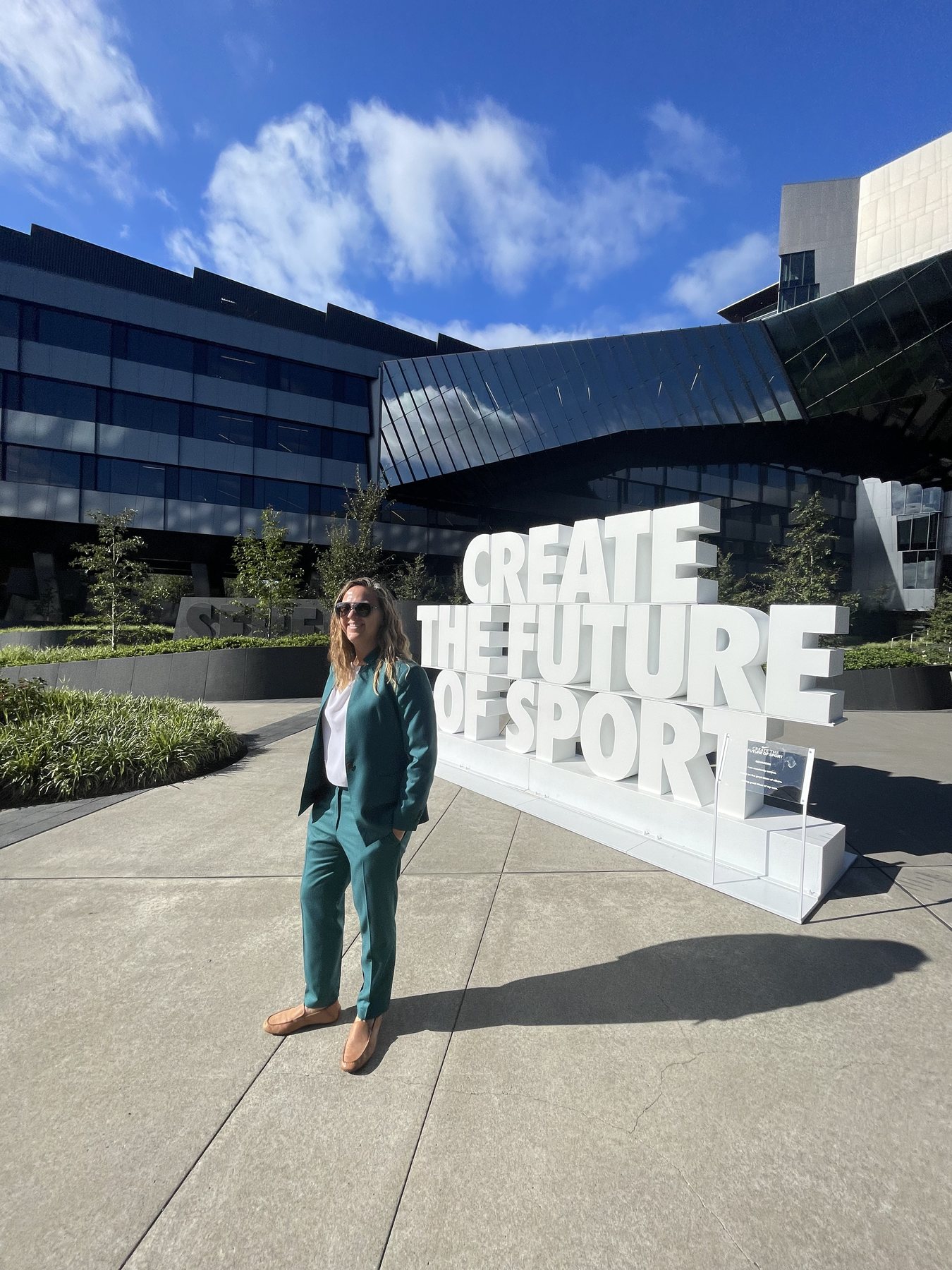 Dr. Emily Sauck standing in front of a sign reading 'Create the Future of Sport'